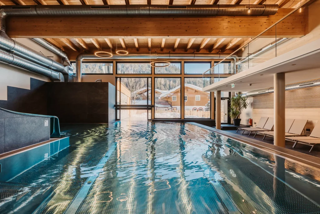 Stimmungsvolle Aufnahme des Indoor-Pools im Hofgut Wagrain mit Blick ins verschneite Tal – wohltuende Wärme, modernes Design und ein einzigartiger Ort zum Innehalten.