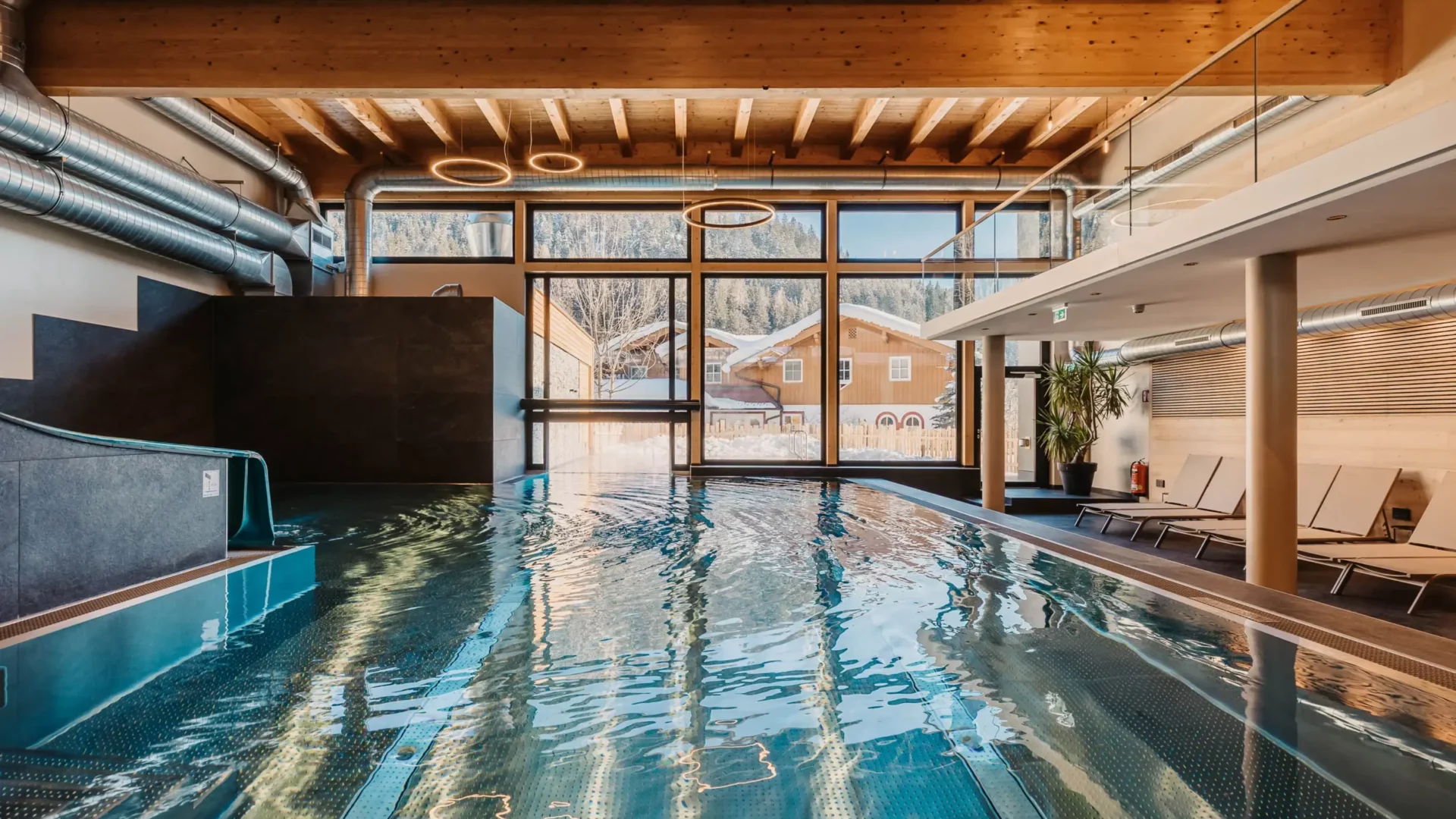 Stemningsbillede af den indendørs pool på Hofgut Wagrain med udsigt over den snedækkede dal - hyggelig varme, moderne design og et unikt sted at stoppe op et øjeblik.