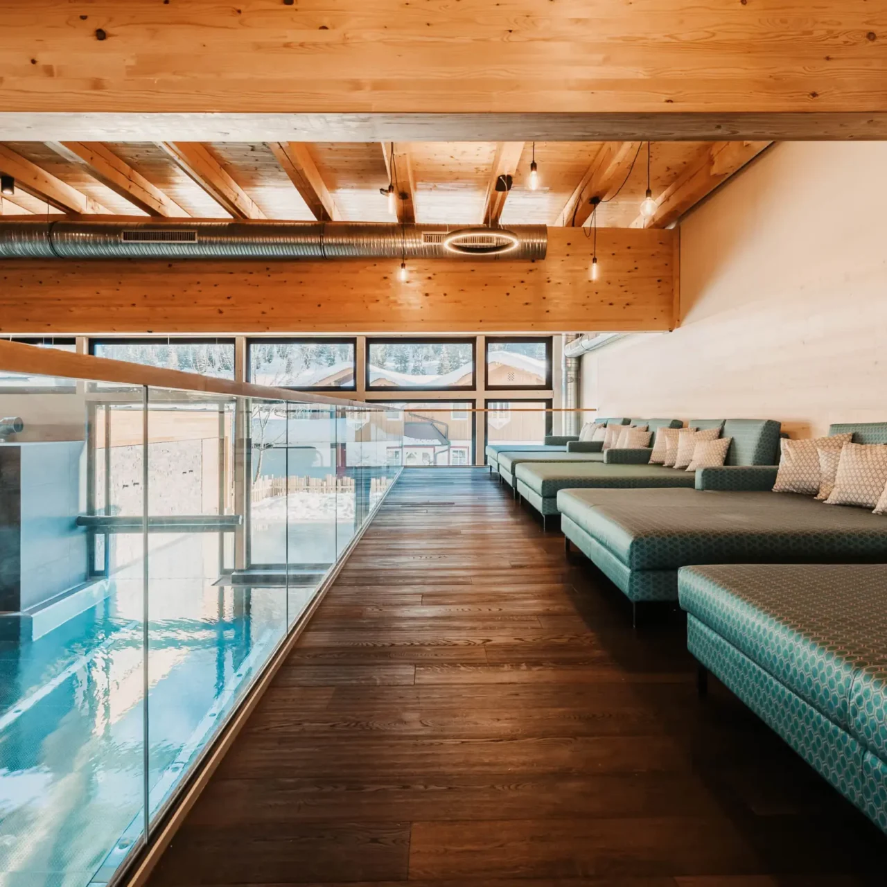 Ruhige Wellnesslounge mit gemütlichen Liegen und Blick auf den Indoorpool im Hofgut Wagrain.