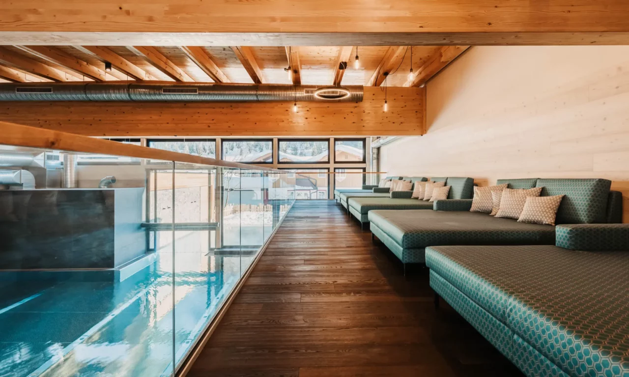 Ruhige Wellnesslounge mit gemütlichen Liegen und Blick auf den Indoorpool im Hofgut Wagrain.