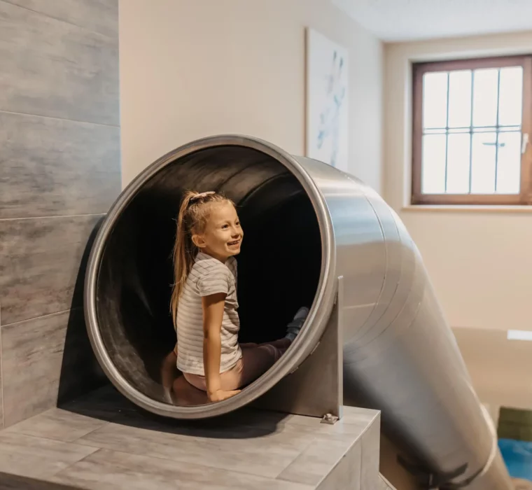 Mit einem Lächeln ins Abenteuer: Fröhliche Rutschpartie auf der Indoor-Rutsche im Hofgut Wagrain – Spaß und Action für kleine Entdecker.