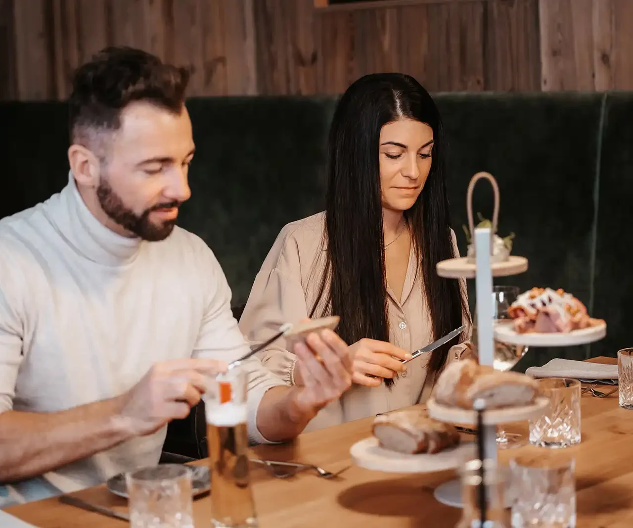 Ein Paar sitzt zusammen im Restaurant und greift nach Brot, während sie lächeln und sich ansehen.