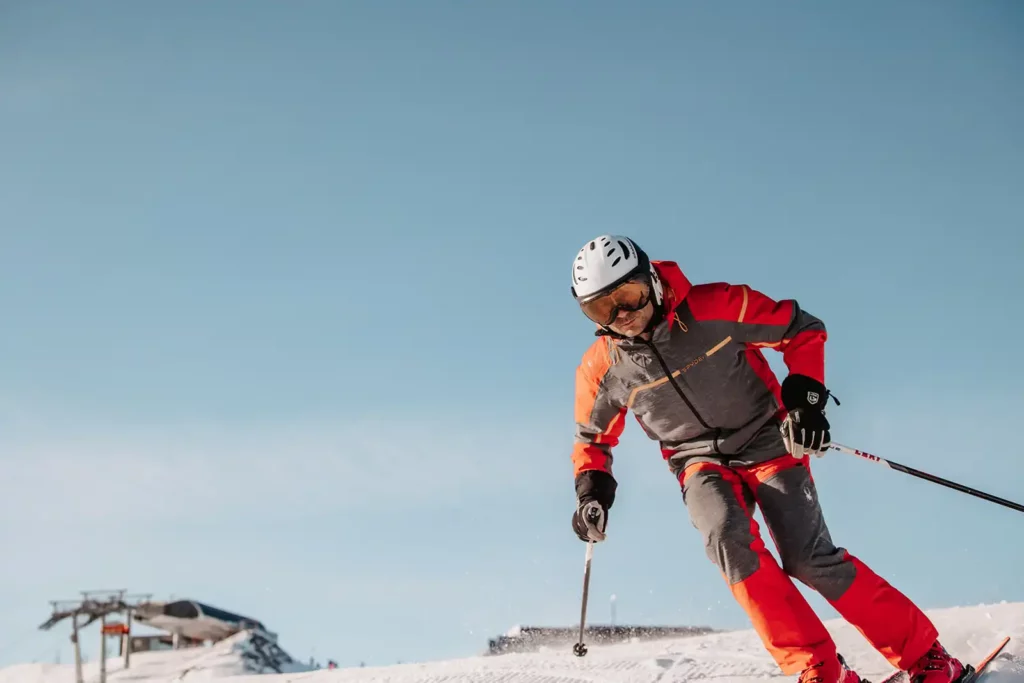 Skier in a red suit carving on the piste in Ski Amadé.