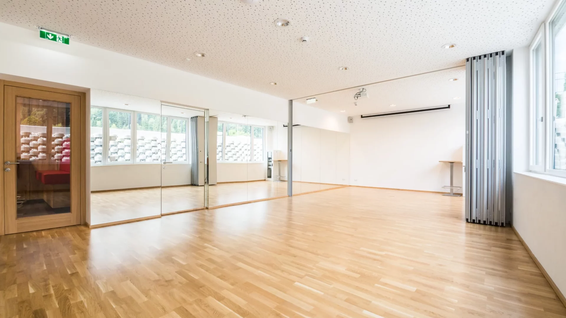 Bright exercise room with parquet flooring, mirrored wall and natural light - ideal for yoga, dance or seminars
