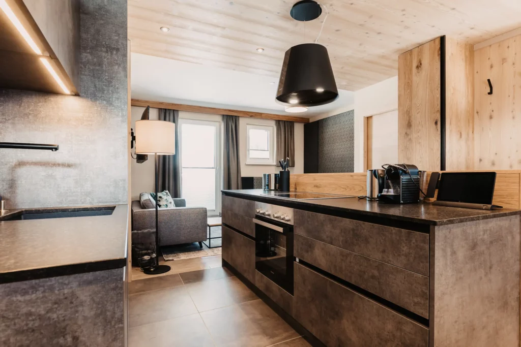 Design-Küche mit hochwertigen Geräten und Blick in den Wohnbereich im Apartment Lärche im Hofgut Wagrain.