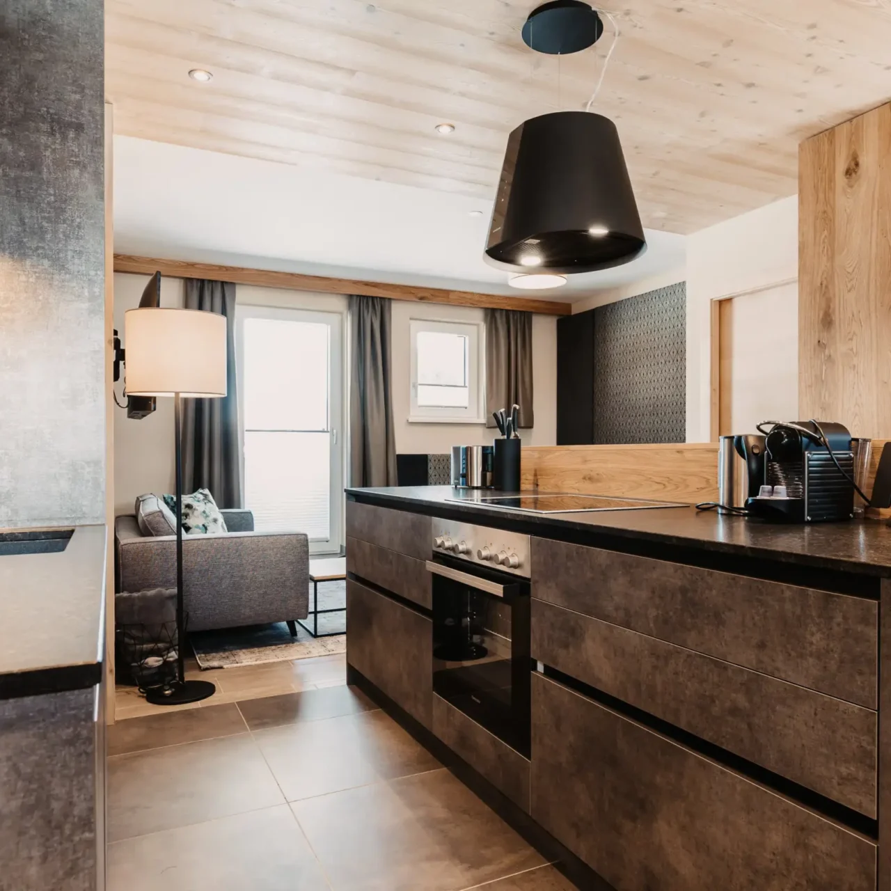 Design-Küche mit hochwertigen Geräten und Blick in den Wohnbereich im Apartment Lärche im Hofgut Wagrain.