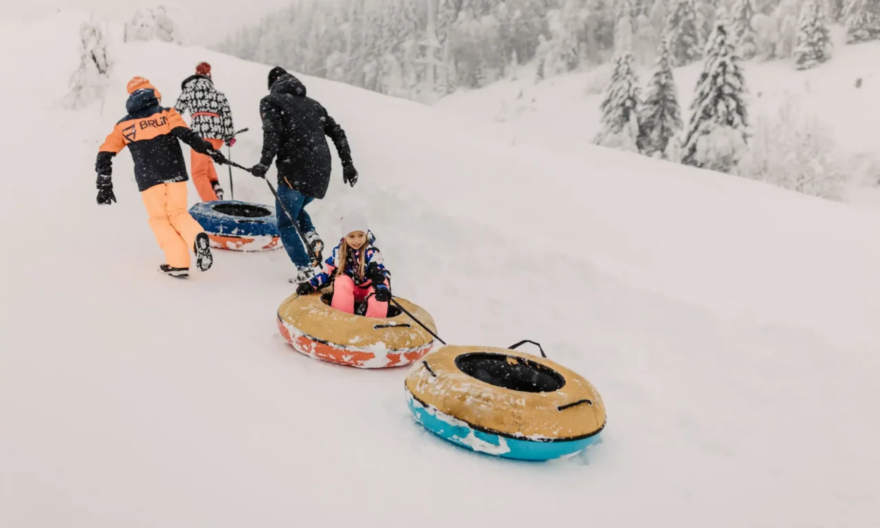 Rodelspaß im Schnee – Kinder beim Snowtubing-Abenteuer mit der Familie im verschneiten Winterparadies des Hofgut Wagrain.