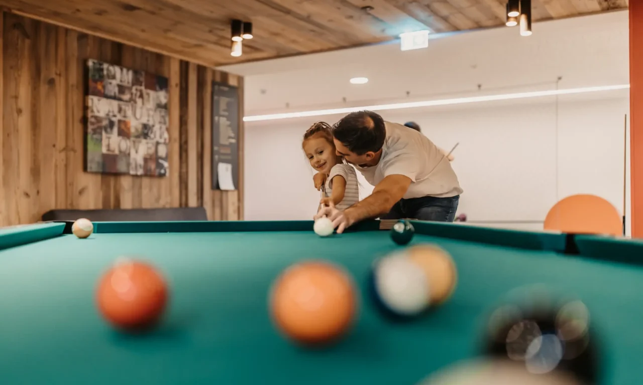 Gemeinsamer Spaß beim Billard – Vater und Tochter genießen wertvolle Familienzeit in der Games Area des Hofgut Wagrain.