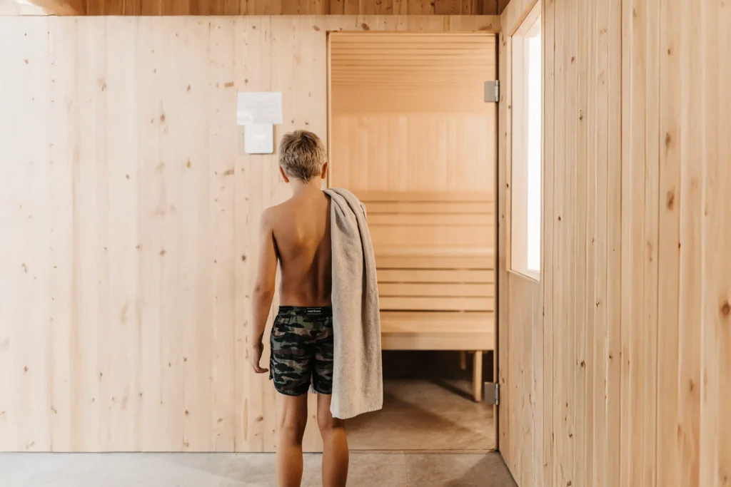 Kind in dunkler Badehose vor der Familien Textilsauna im Hofgut Wagrain.
