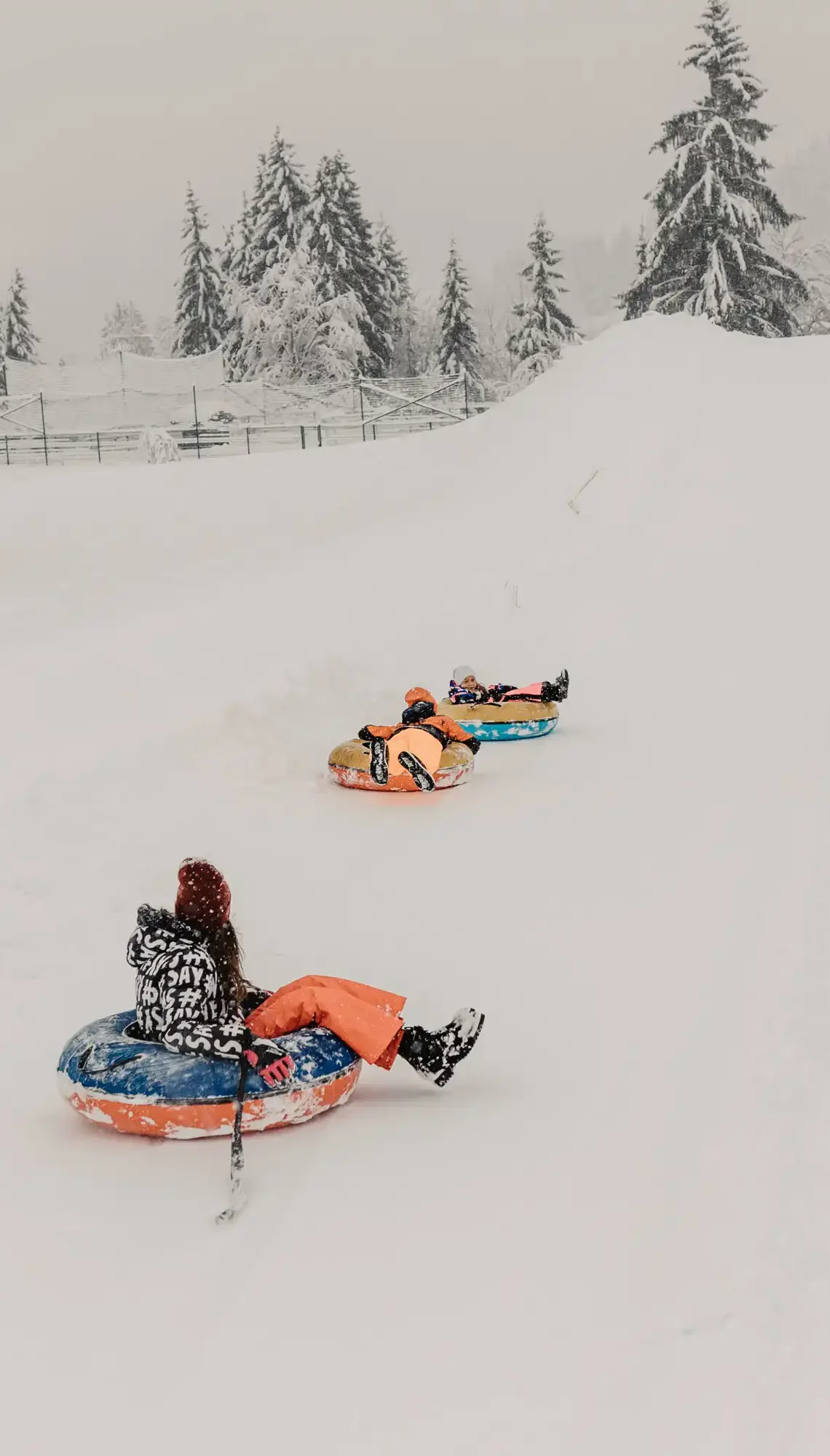 kinder beim snowtubing auf verschneiter bahn am hofgut wagrain