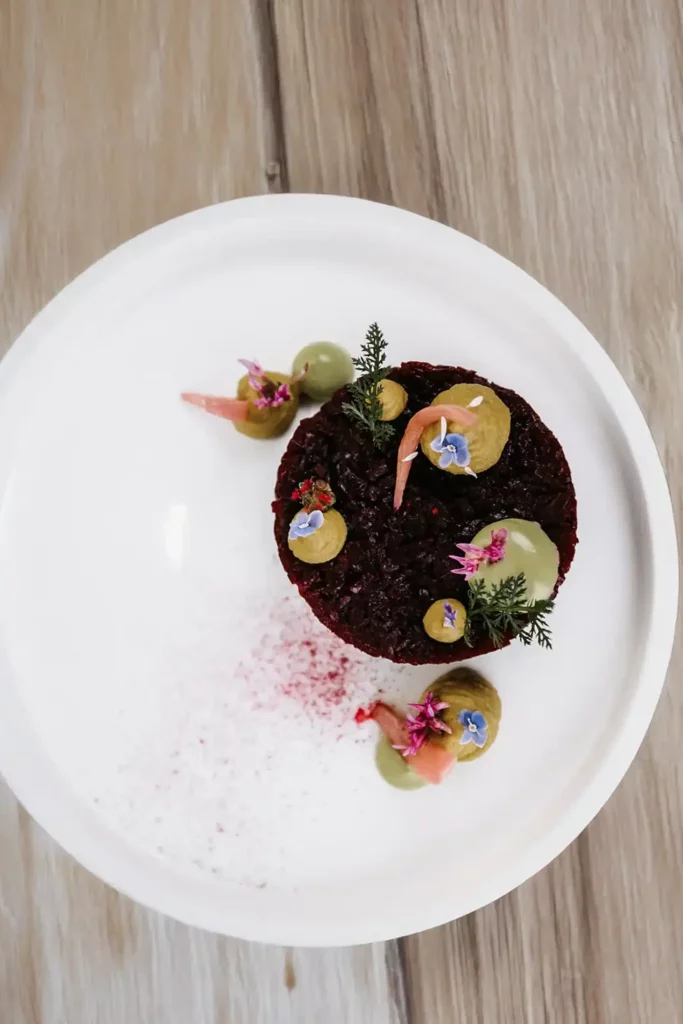 Hovězí tatarák s aioli, cibulí a bylinkami na bílém talíři v restauraci vamoos v Hofgut.