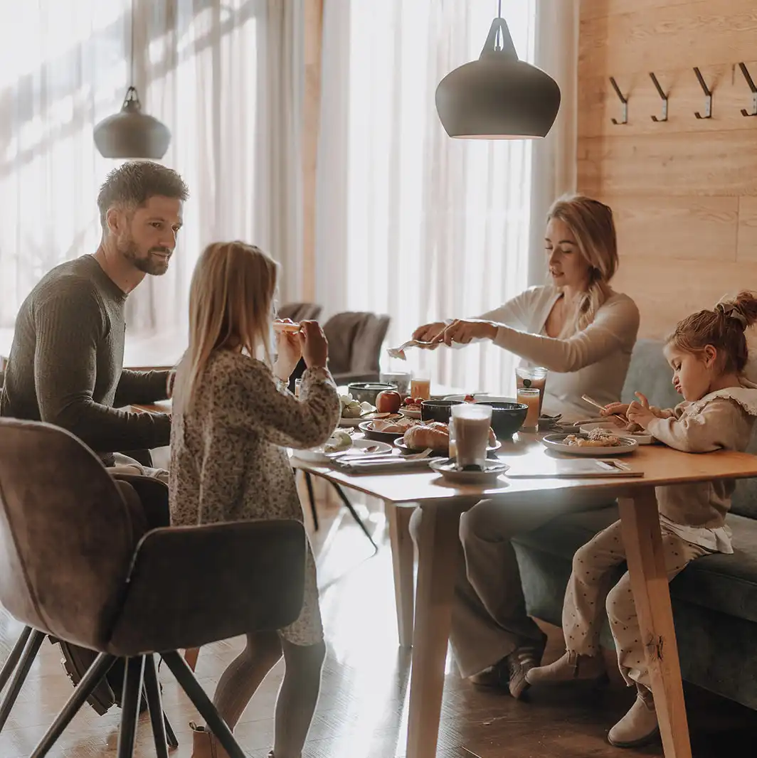 Vierköpfige Familie sitzen am Frühstückstisch beim Genießerfrühstück im Hofgut Wagrain- Restaurant vaMoos.