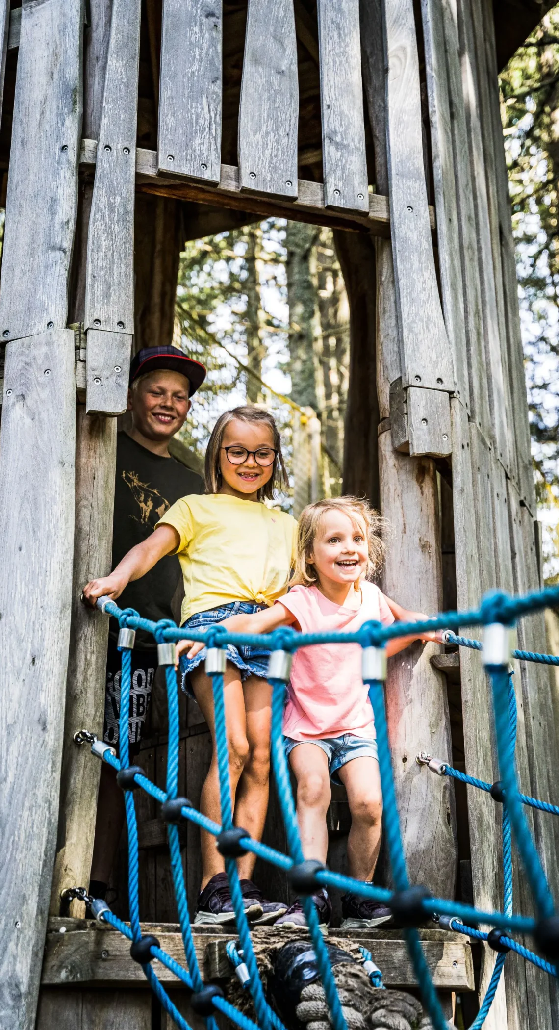 Kinder auf einer Hängebrücke am Spielturm im Wald