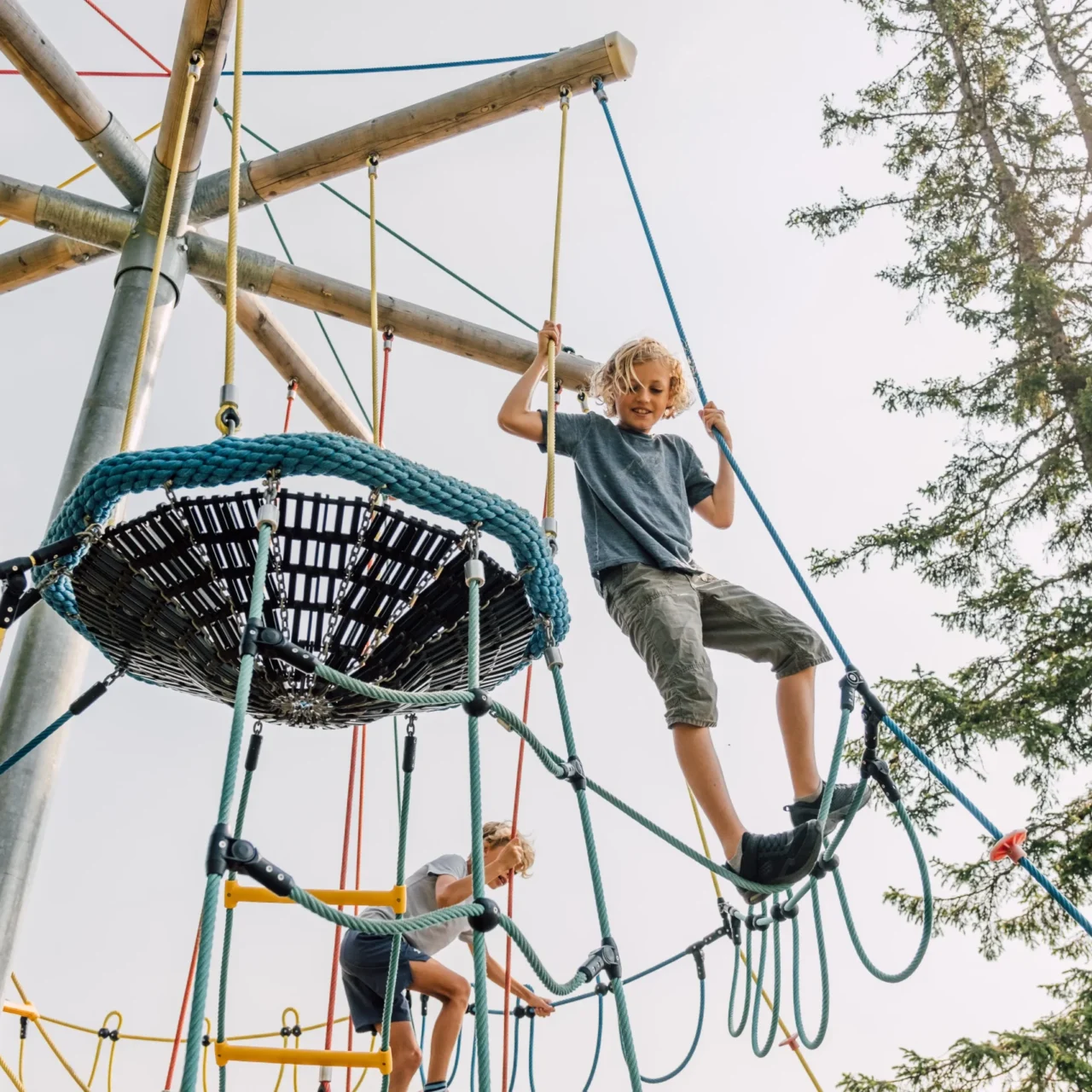 Kind klettert auf einem Abenteuerspielplatz mit Seilen und Holzstrukturen am Geisterberg.