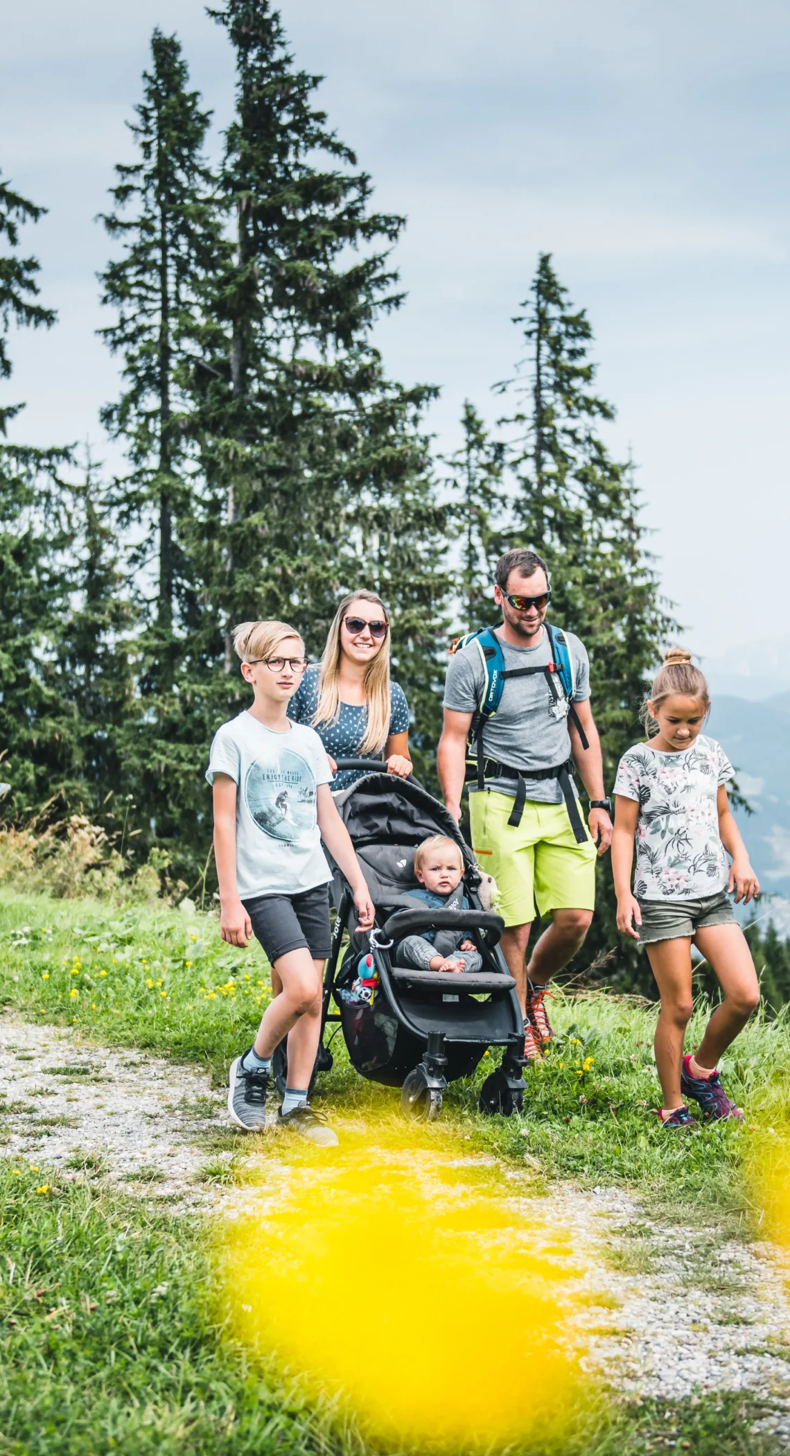 Familie mit Kinderwagen wandert auf einem Panoramaweg am Grafenberg mit Blick auf die Alpen