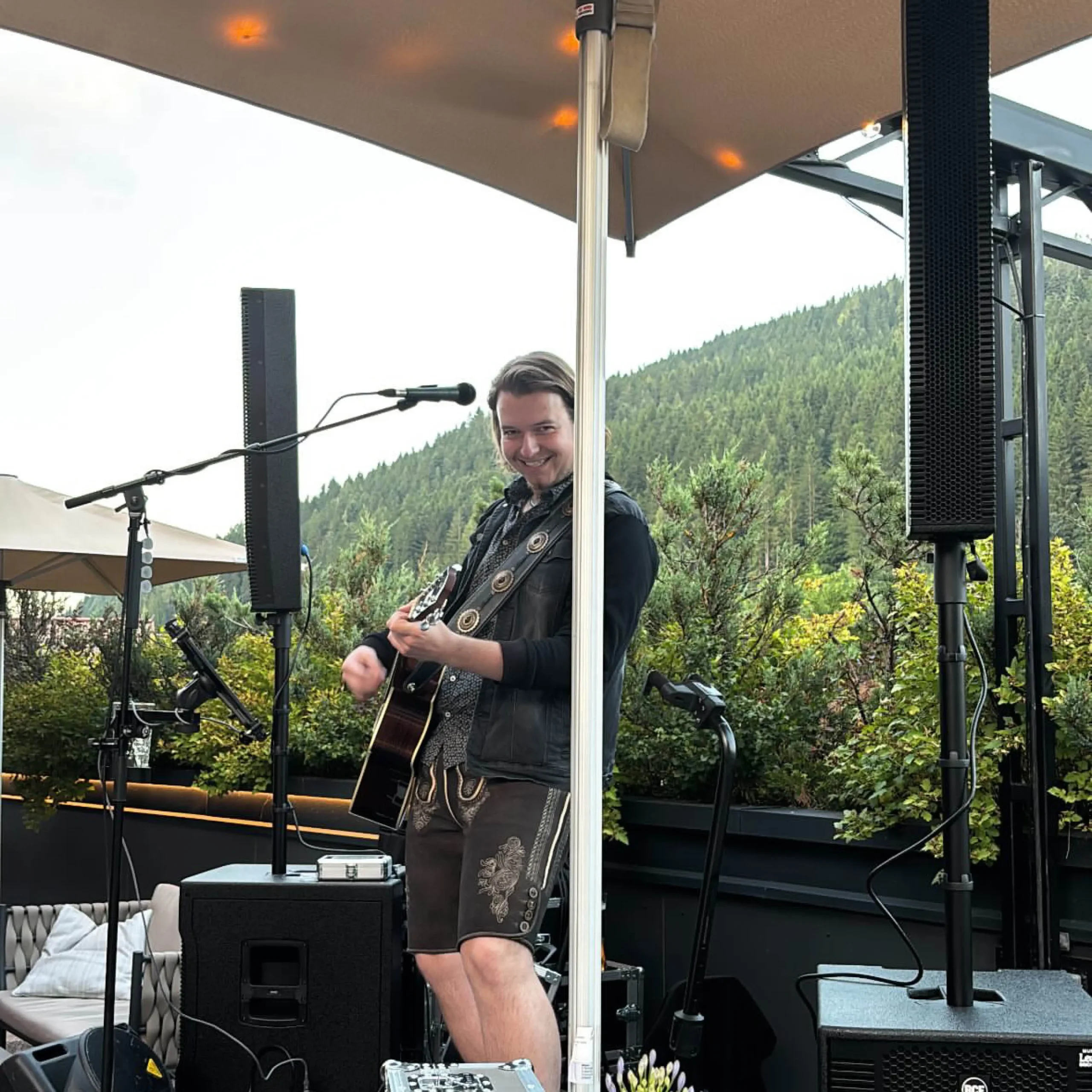 Gitarrist spielt Live-Musik auf der Terrasse des Restaurants Vamoos im Hofgut Wagrain vor alpiner Bergkulisse.