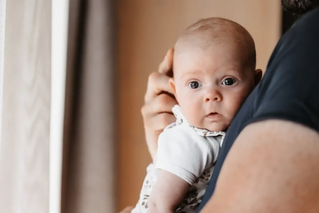 Süßes Baby getragen an Papas Brust.