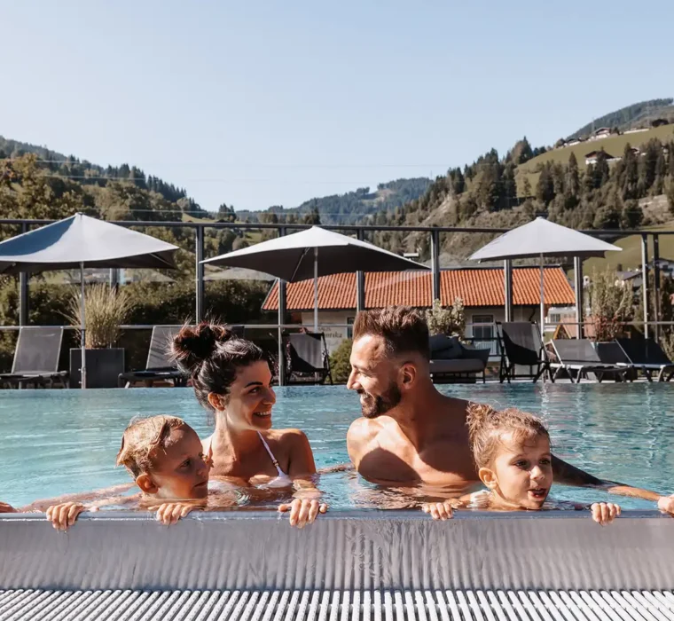 Familie im Sommerurlaub im Rooftop Pool vom Hofgut Wagrain.
