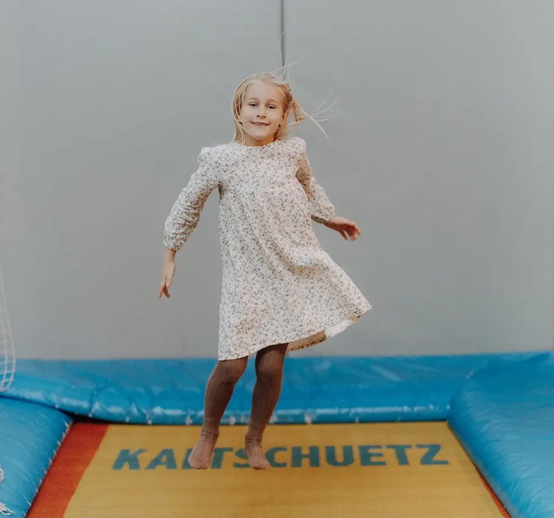 Ein Kind hüpft hoch auf dem Trampolin in der Indoor-Spielewelt des Hofgut Wagrain.